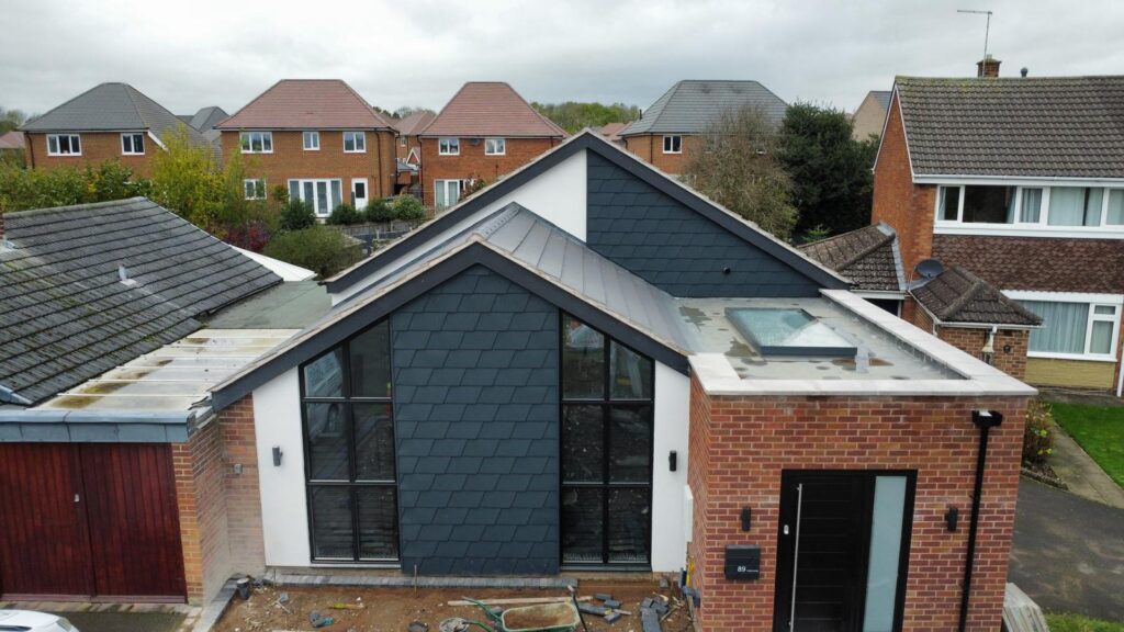 Renovated bungalow with twin gable design, modern black tile cladding, flat roof porch, and roof lantern for natural light.