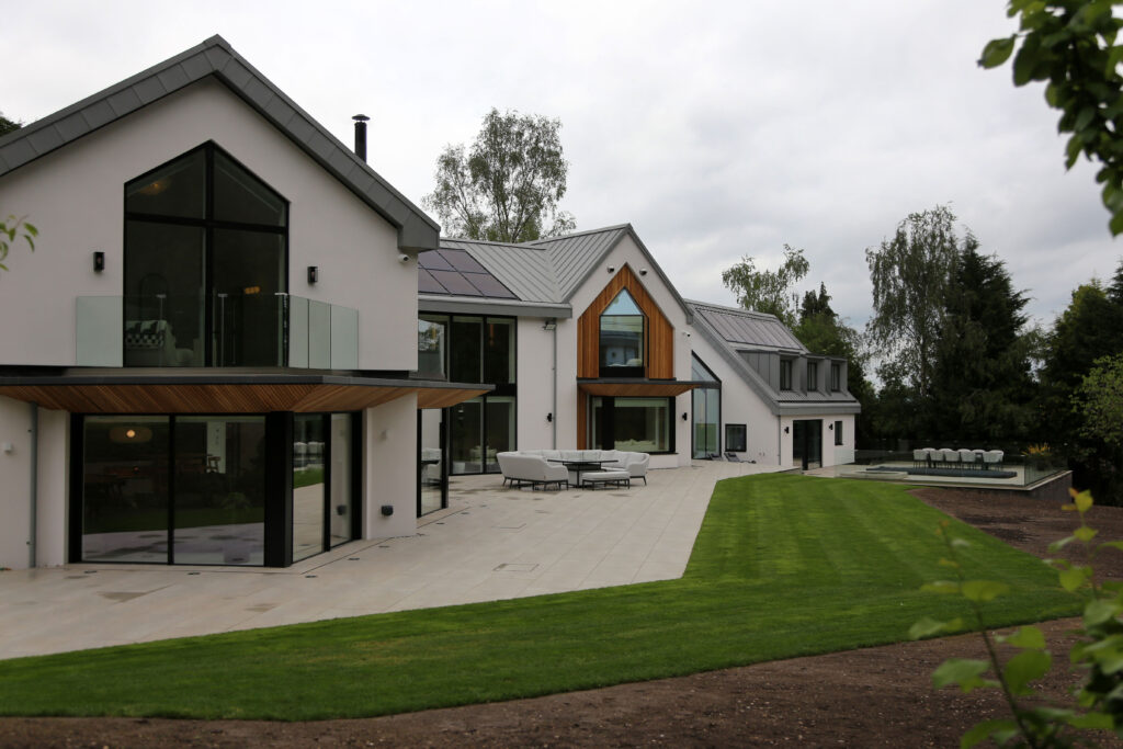 Rear elevation of Woodlands in Draycott in the Clay, Staffordshire. House is white with multiple balconies and gables. Large patio area. This house has under gone major renovations and extensions all work carried out by Allsopp Construction.