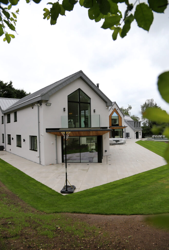 Rear elevation of Woodlands in Draycott in the Clay. White gable end with large triangular window and standing seam aluminium roof.