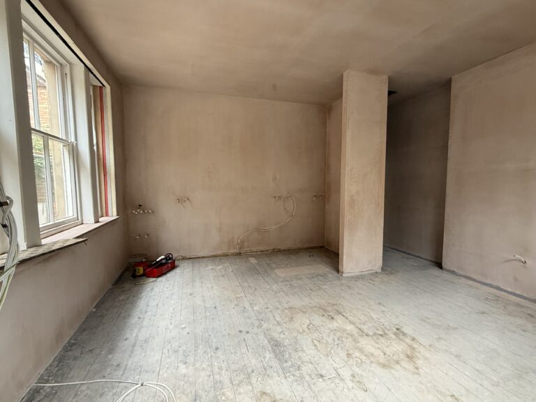 Empty newly plastered open-plan kitchen and living area taking shape in the first new home at the Liversage Trust almshouses on London Road, Derby.