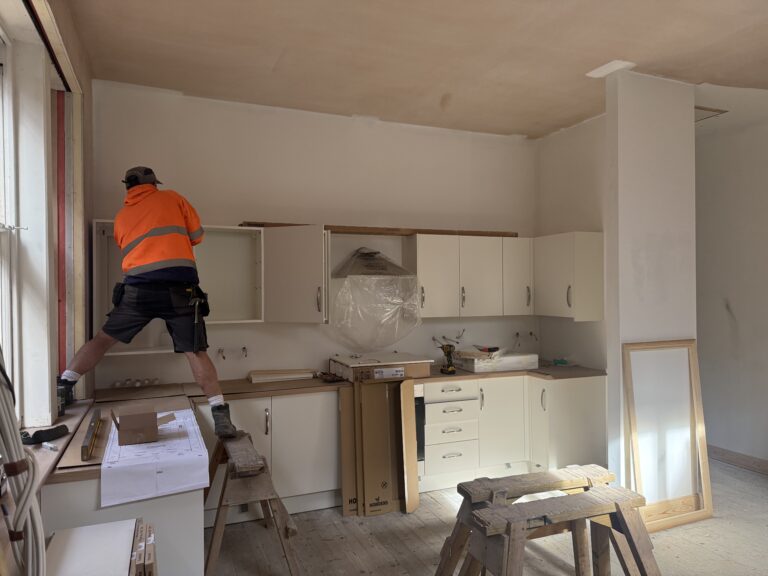 Liversage Trust Almshouses Refurbishment Project kitchen being installed. Cream called kitchen units beng fitted on to a new plastered wall.